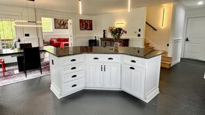 A modern kitchen with white cabinetry, granite countertops, and pendant lighting.