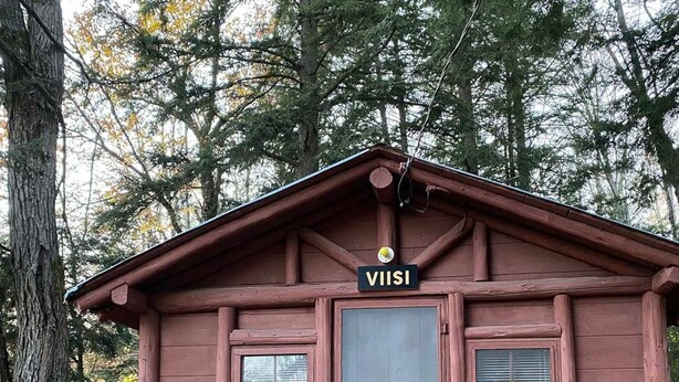 En lille hytte med et skilt, der siger "VIIISI", og en grøn plastikstol foran.