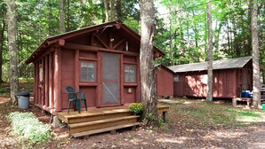 Un rustico chalet con veranda in legno, una sedia verde e un piccolo vaso di fiori.