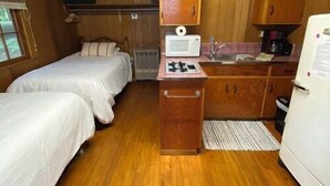 Una cabina compatta con due letti, un angolo cottura e un bagno piccolo.
