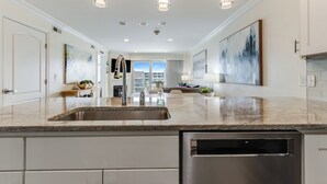 A modern kitchen with a large island, stainless steel appliances, and pendant lighting. - Luxury water-view condo with high-end finishes and beach toys included! (Dewey Beach)