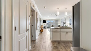A modern kitchen with white cabinetry, a central island, and a wooden floor. - Luxury water-view condo with high-end finishes and beach toys included! (Dewey Beach)