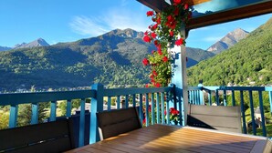 A wooden deck with a table and chairs, overlooking a mountainous landscape with a clear sky.