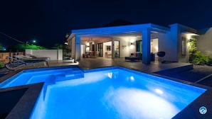 Een modern huis met een zwembad, buiten zitplaatsen en een overdekt terras.