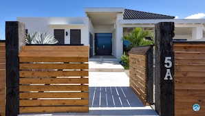 Een modern huis met een houten poort, een blauwe deur en een bord met het nummer 5A.