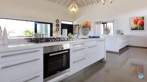 Een moderne keuken met een gasfornuis, oven en witte kastjes.