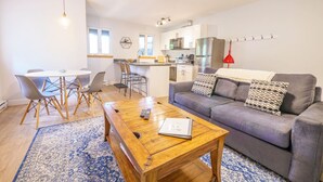Una sala de estar moderna con un sofá gris, una mesa de centro de madera y una alfombra azul estampada.