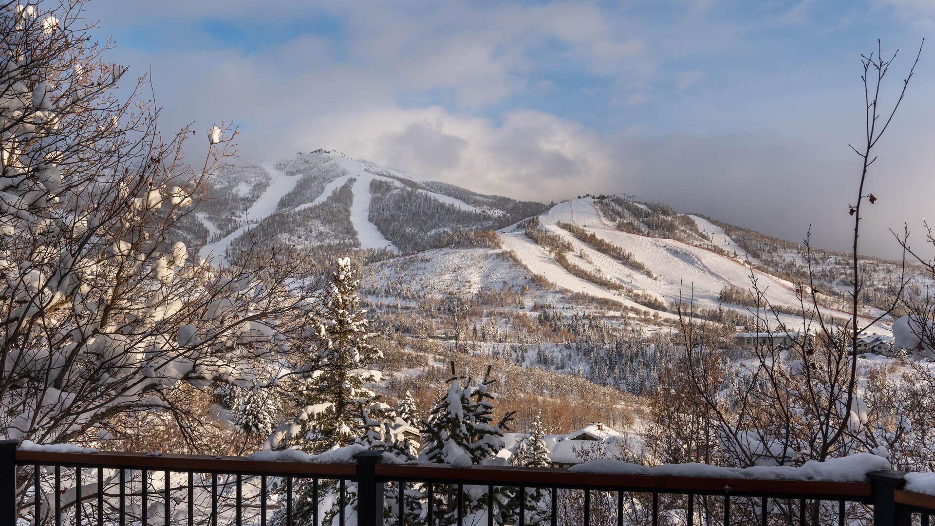 A mountainous landscape with snow-covered slopes and a ski trail.