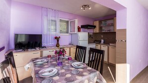 A compact kitchen with a dining area, featuring a table set for four, a refrigerator, and a microwave.