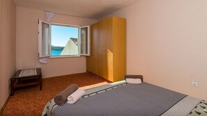 A bedroom with a bed, a window, a wardrobe, and a small table.