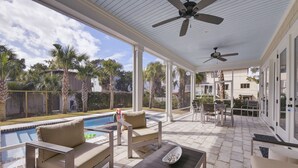 Un patio techado al aire libre con piscina, mobiliario y ventiladores de techo.