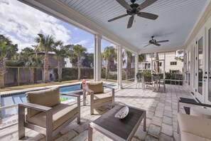 Relax in a shaded outdoor space with a sofa, chairs, and table overlooking the swimming pool.