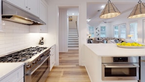 Una cocina moderna con armarios blancos, electrodomésticos de acero inoxidable y suelo de madera.