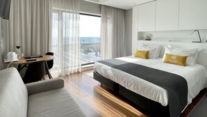 A modern hotel room with a large bed, a sofa, a desk, and a view of the city. - Praia de Santos, Exclusive Villa, Sea-sided with swimming pool, Azores Islands (São Roque)