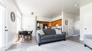 A modern living room with a grey sofa, a dining table with chairs, and a kitchen in the background. - Beautiful, Sparkling Clean 3 BR, 2.5 BA Townhome!! (Providence)
