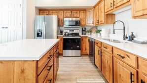 A modern kitchen with wooden cabinets, stainless steel appliances, and a white countertop. - Beautiful, Sparkling Clean 3 BR, 2.5 BA Townhome!! (Providence)