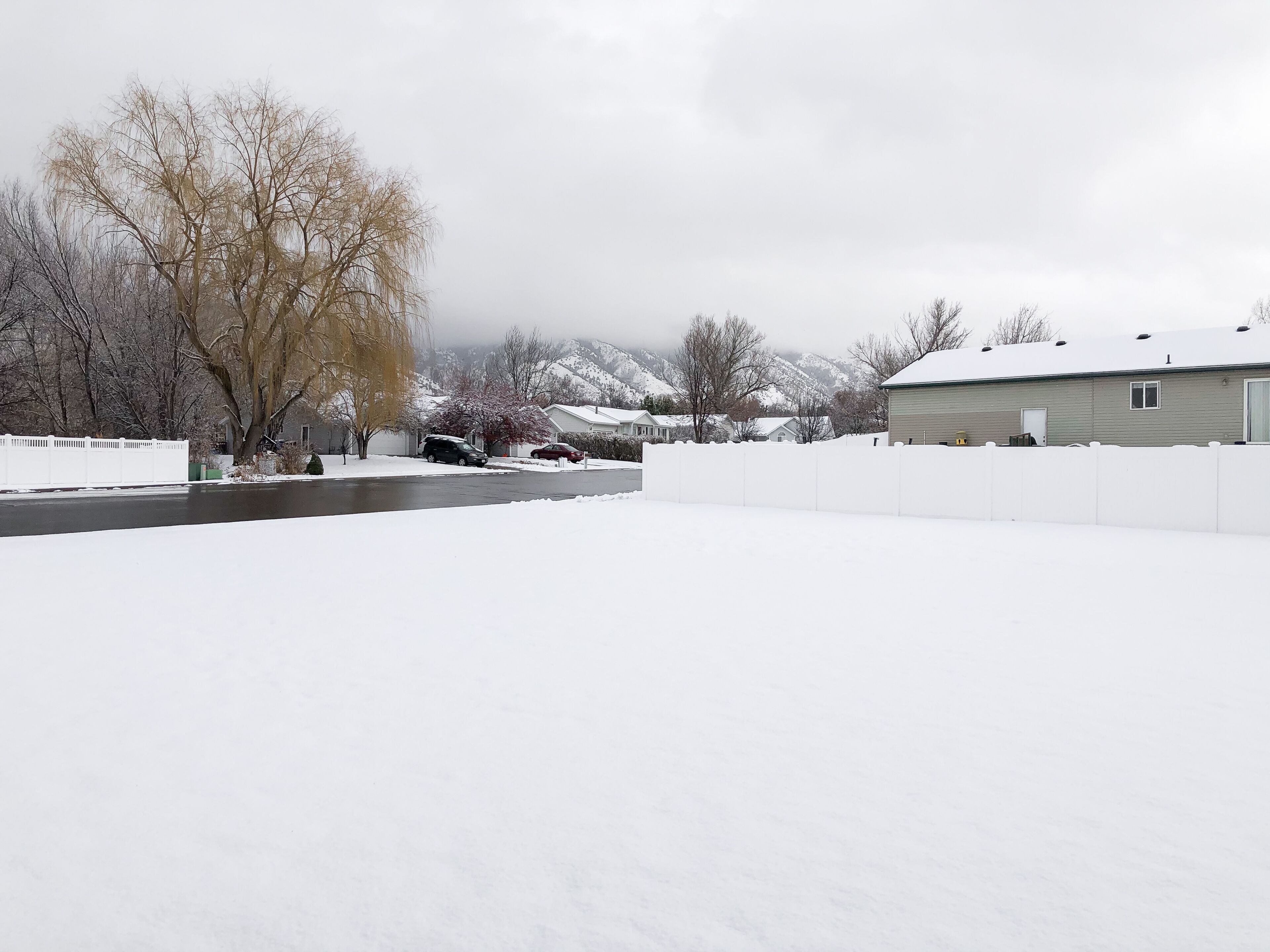 Un quartier résidentiel où le sol, les maisons et une clôture sont recouverts de neige.
