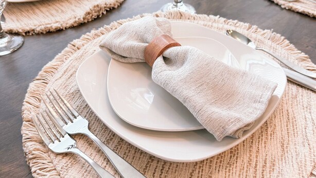 A dining table set with white plates, silverware, and glassware on beige placemats. - Beautiful, Sparkling Clean 3 BR, 2.5 BA Townhome!! (Providence)