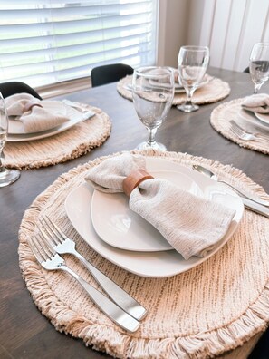A dining table set with white plates, silverware, and glassware on beige placemats. - Beautiful, Sparkling Clean 3 BR, 2.5 BA Townhome!! (Providence)