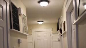 A hallway with a wooden floor, white walls, and a white door at the end. - Clean & Simple (Lubbock)