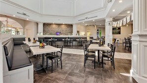 Een ruim restaurant met hoge plafonds, een centrale stenen muur en meerdere zithoeken, waaronder perken en tafels.