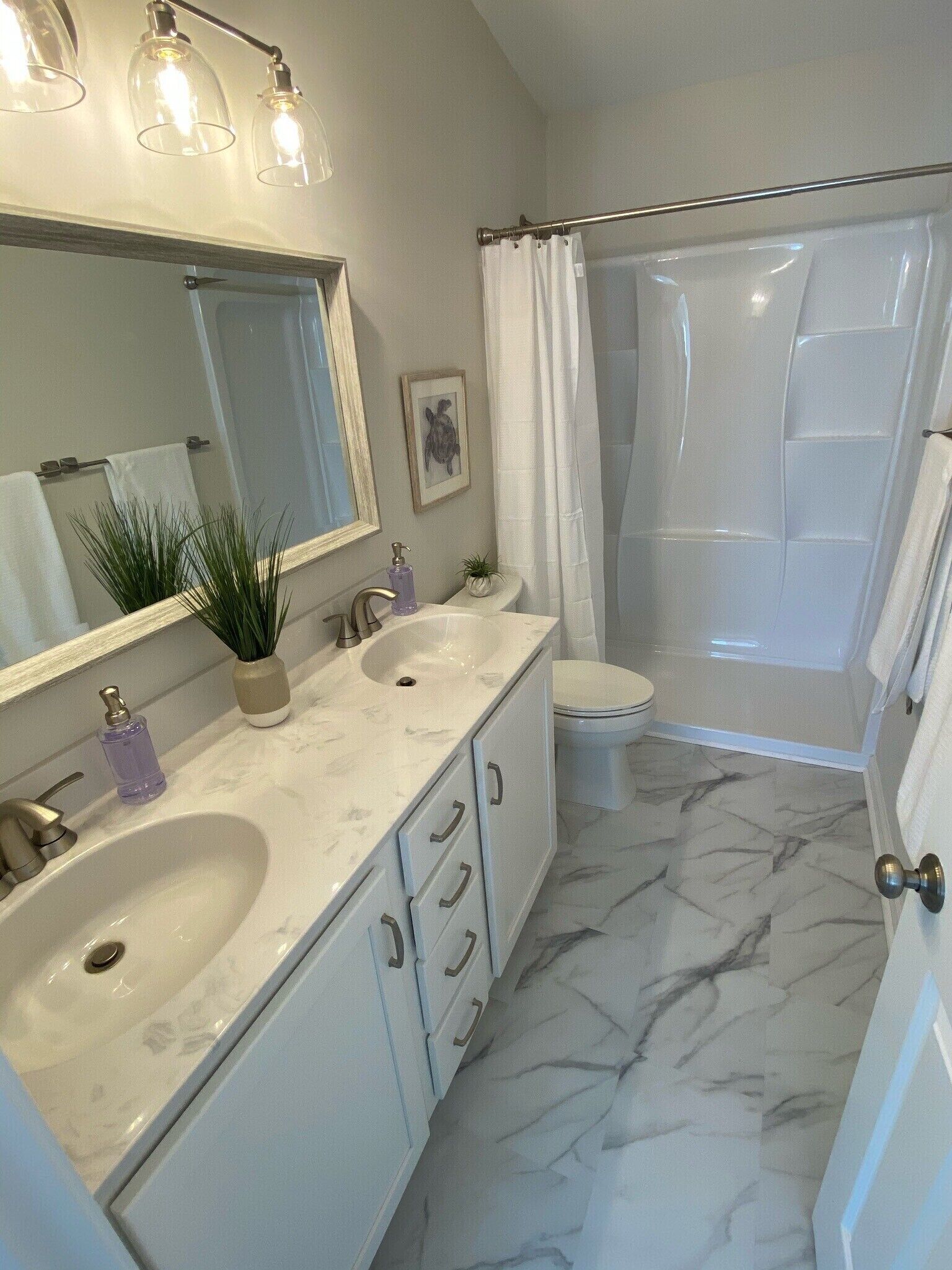 Ein Badezimmer mit zwei Waschbecken, einer Toilette, einer Dusche und einem Spiegel.