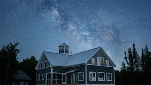 A house with a large window, a small tower, and a porch. - Bois Blanc Island Lighthouse Home. Iconic Sunset Views of the Mackinac Bridge! (Bois Blanc Island)
