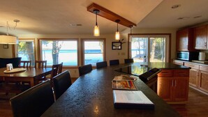 A spacious kitchen with a large island, wooden cabinets, and a view of the ocean. - Waterfront gem, sandy beach, modern kitchen, large great room, free firewood (Sturgeon Bay)