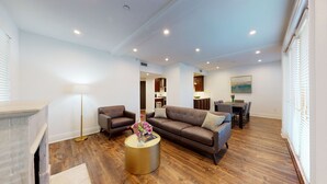Een moderne woonkamer met een bruine leren bank, een rond goudkleurig bijzettafeltje en een vloerlamp.