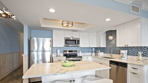 Una cocina moderna con armarios blancos, electrodomésticos de acero inoxidable y una isla central con asientos.