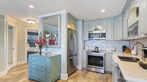 A modern kitchen with light blue cabinets, stainless steel appliances, and a wooden floor. - Newly Renovated Condo 305, Your Luxurious BEACH FRONT Paradise - Crystal Dune (Destin)