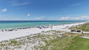 A beach with a wooden walkway leading to the water, umbrellas, and beach chairs. - Newly Renovated Condo 305, Your Luxurious BEACH FRONT Paradise - Crystal Dune (Destin)