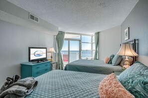 A hotel room with two beds, a television, a window with curtains, and a view of the ocean. - Amazing View Ocean Front Condo-Completely Renovated, 16th Floor (Myrtle Beach)