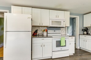 A kitchen with white cabinetry, a microwave, a stove, and a refrigerator.