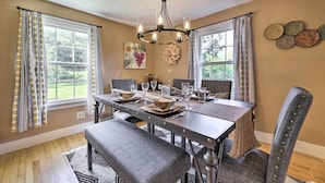A dining room with a wooden table set for six, surrounded by upholstered chairs. - Hampton 'Quiet Corner Cottage' w/ Fireplace & Yard (Hampton)