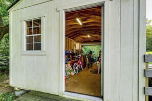 Ein kleines, einstöckiges Gebäude mit Holzfassade und einem sichtbaren Fenster. Darin befinden sich ein Fahrrad und ein Paar Schuhe.
