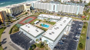 Un hotel con varios pisos, una piscina en la azotea y vista al mar.
