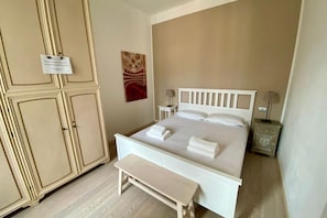 Un dormitorio con cama, un banco, una mesita de noche, un armario y un letrero en la pared.