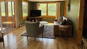 A living room with a television, a sofa, a chair, and a coffee table.