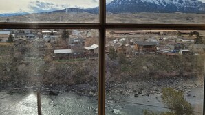 A view through a window of a town with houses, a river, and mountains in the background. - Yellowstone Beauty Overlooking Yellowstone River BRAND NEW Gardiner, MT  (Gardiner)