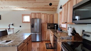 A modern kitchen with wooden cabinets, stainless steel appliances, and a granite countertop. - Yellowstone Beauty Overlooking Yellowstone River BRAND NEW Gardiner, MT  (Gardiner)