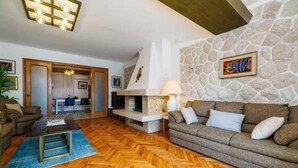 A living room with a stone wall, a fireplace, a sofa, and a herringbone wood floor.