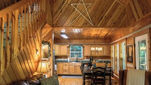 L'interno accogliente di una baita con zona pranzo, pareti in legno e un design del soffitto a forma di stella.