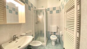 Un baño con lavamanos, bidé, inodoro y ducha.