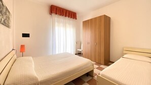 Un dormitorio con dos camas, un armario, un escritorio y una silla.