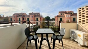 A rooftop terrace with a table and chairs, an air conditioning unit, and a view of neighboring buildings. - Appartamento Treporti 4 Cavallino- Carraro Immobiliare Jesolo (Cavallino)