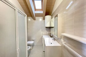 Un baño moderno con tragaluz, inodoro, lavamanos y espejo.
