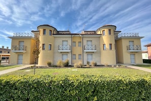 A multi-story residential building with a symmetrical facade, balconies, and a well-maintained lawn.
