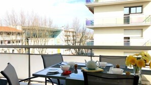 En balkon med et morgenmadsbord, stole og udsigt over bybilledet.