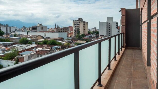 A balcony with a view of a cityscape, including various buildings and a church spire.